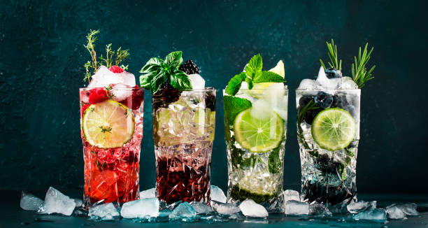 Cocktails drinks. Classic alcoholic long drink or mocktail highballs with berries, lime, herbs and ice